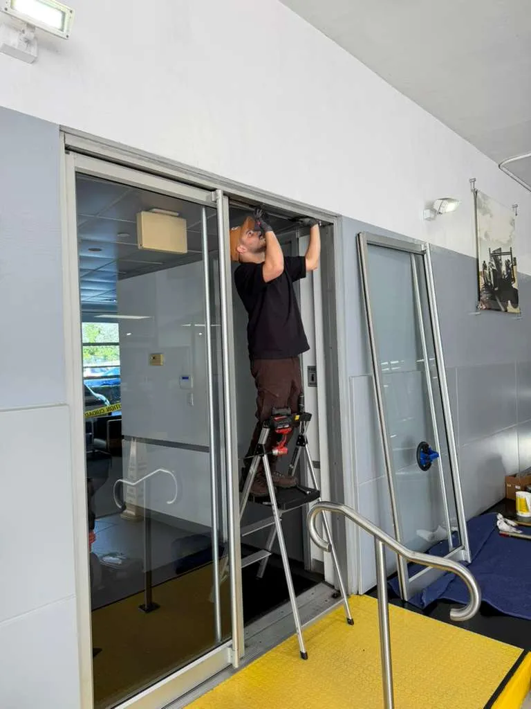 JDM technician servicing a commercial entrance door track in Colorado