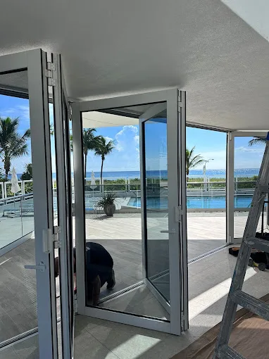 JDM technician installing commercial folding glass doors at a Florida oceanfront property
