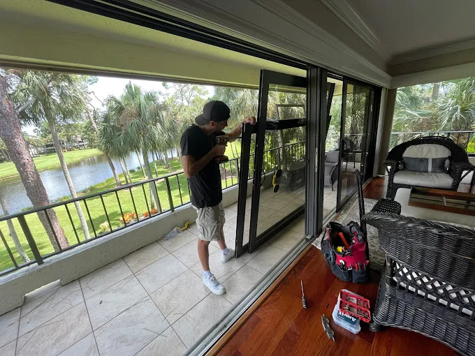 JDM technician servicing a sliding glass door on a Florida lanai overlooking a lake